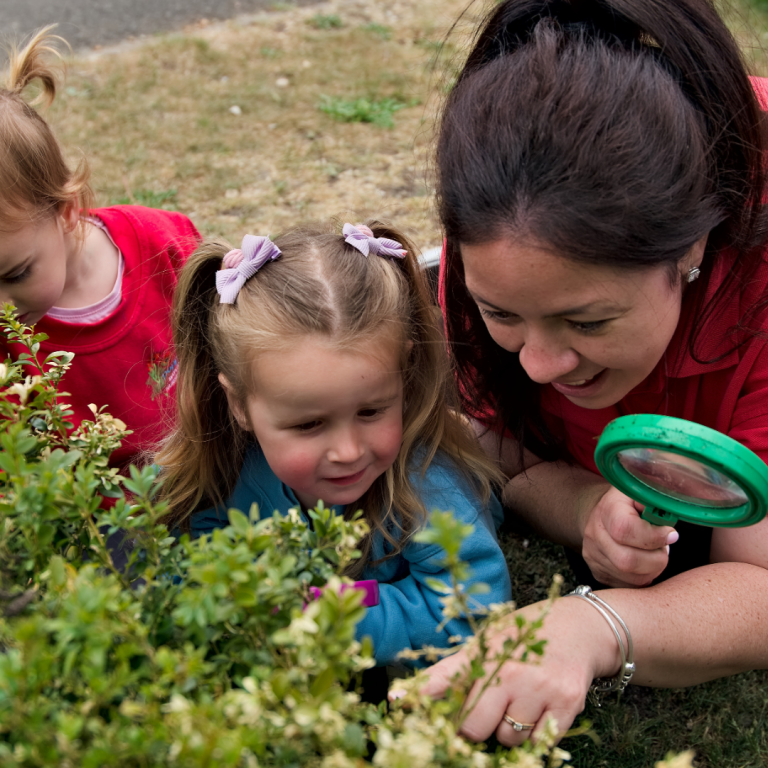 A practitioner at Poppies Nursery exploring with the children in the secure outside space.