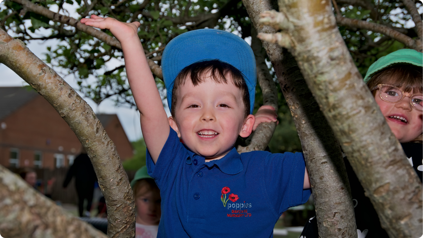Poppies Nursery - the outside play area with a little boy playing in a tree
