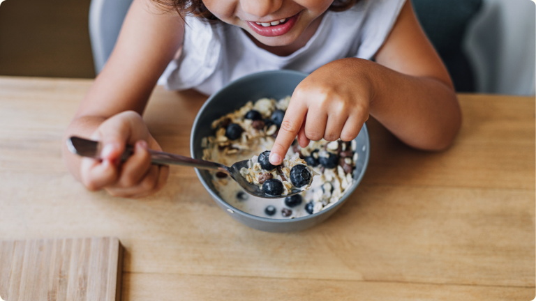 How to Ensure Daycare Has a Healthy Snack Policy - represented by a little girl eating a healthy breakfast