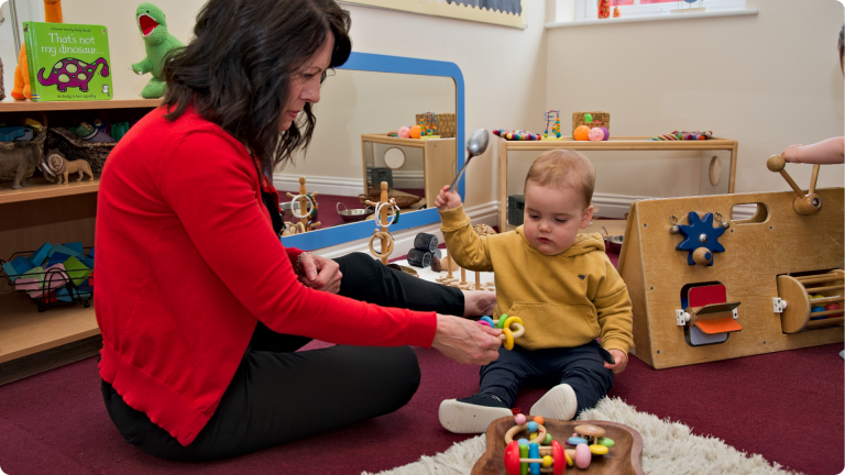 Poppies Nursery worker Vicky playing with a baby in the baby room