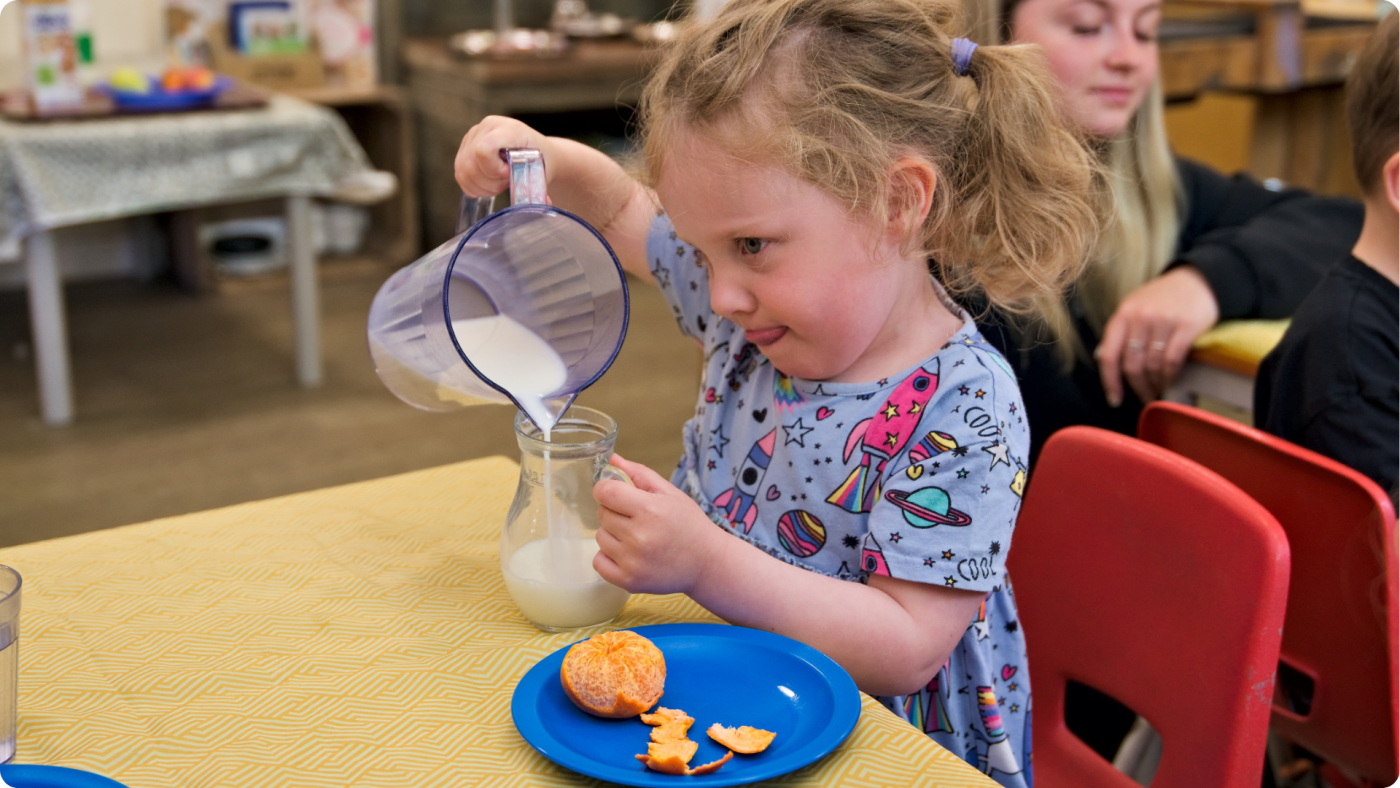 Healthy Eating in the Early Years shown by a 3 year old girl pouring her own milk as a snack