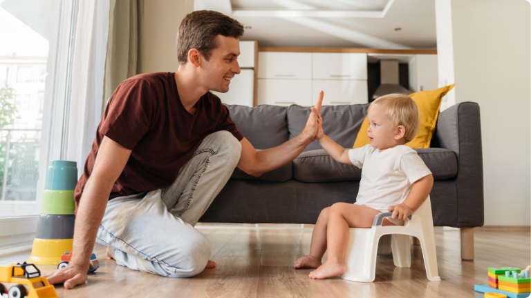 How to start potty training: with encouragement. A father with their child using the potty and high fiving