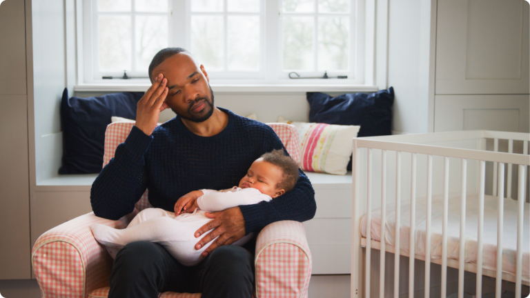 Separation anxiety in infants - a father exhausted trying to keep the baby asleep in his lap