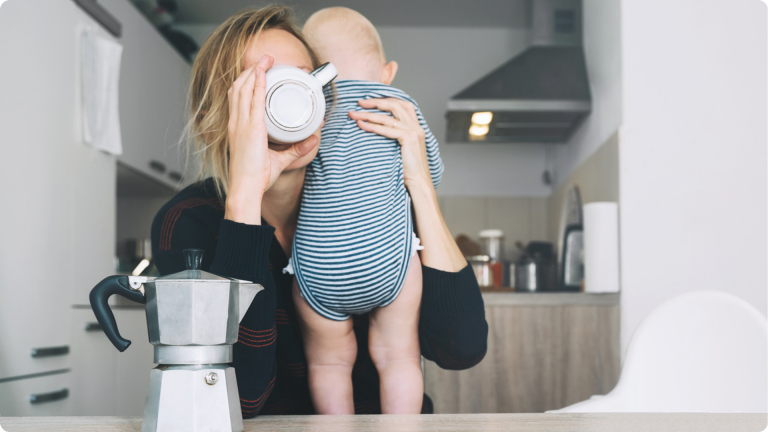 Separation anxiety in infants - woman holding a baby while trying to drink coffee