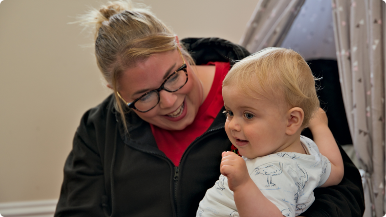 What Makes a Good Nursery Practitioner- shown by a Poppies nursery practitioner playing withe one of the babies