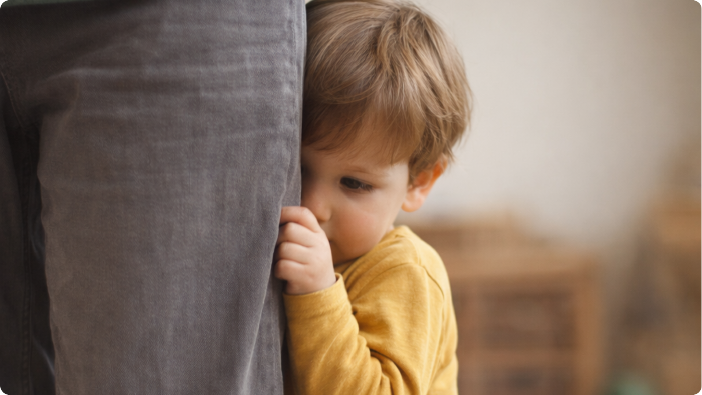 Shy Toddler hidding behind someones leg