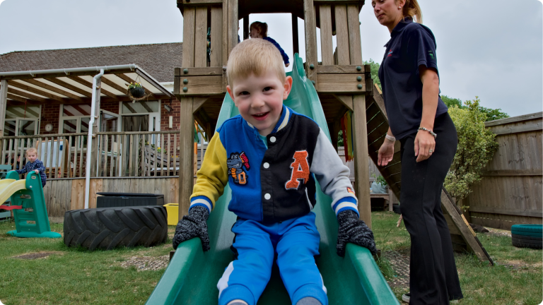 15 Hours Free Childcare shown by a chilod playing on the slide at nursery