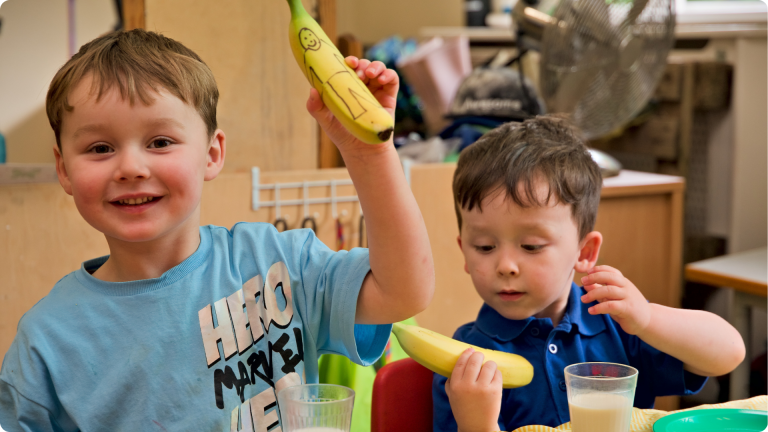 15 Hours Free Childcare shown by 2 children playing with bananas