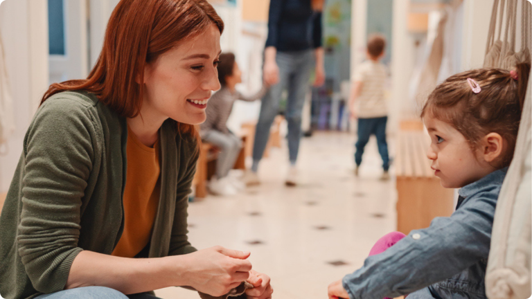 How to Handle Daycare Separation Anxiety shown by a mther and daughter saying godbye in the hallway of a nursery