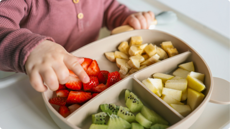 Activities to Promote Independence in Toddlers shown by a child choosing between different fruits on a tray