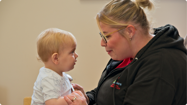 Free Childcare Hours Explained showing a nursery practitioner playing with one of the babies at the Perham nursery
