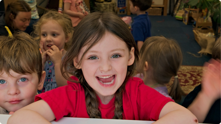 How to Build Confidence in Children shown by a little girl grinning at the camera